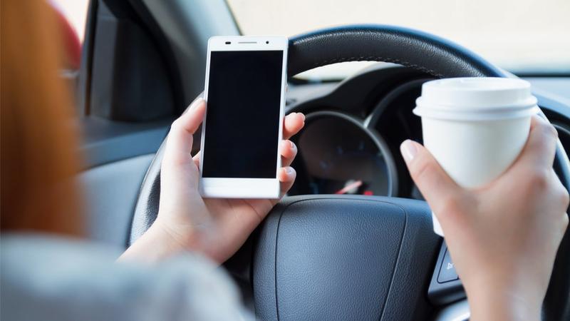 driver with phone and coffee